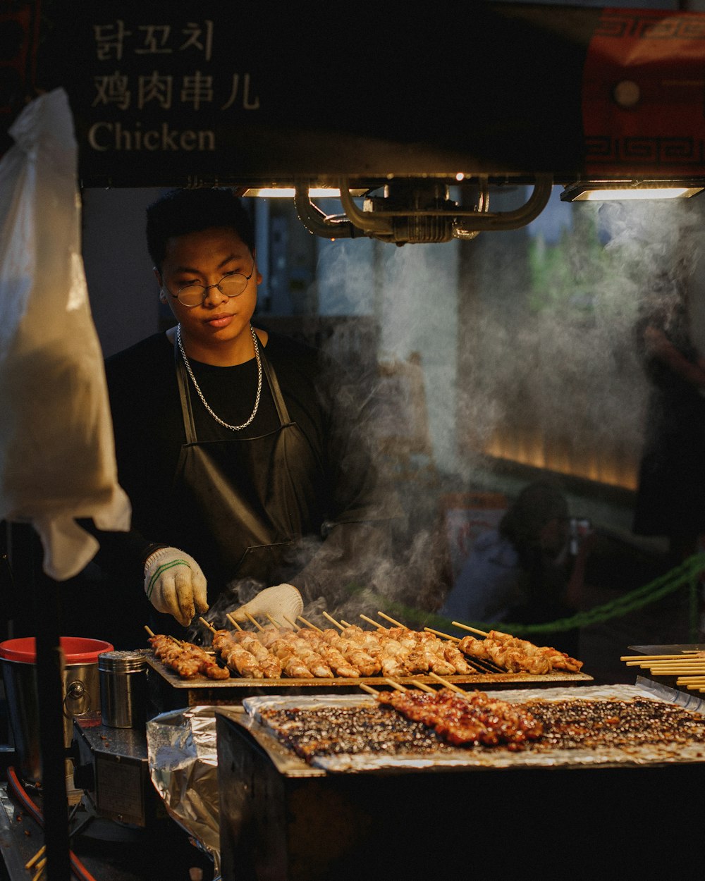 man grilling meat skewers