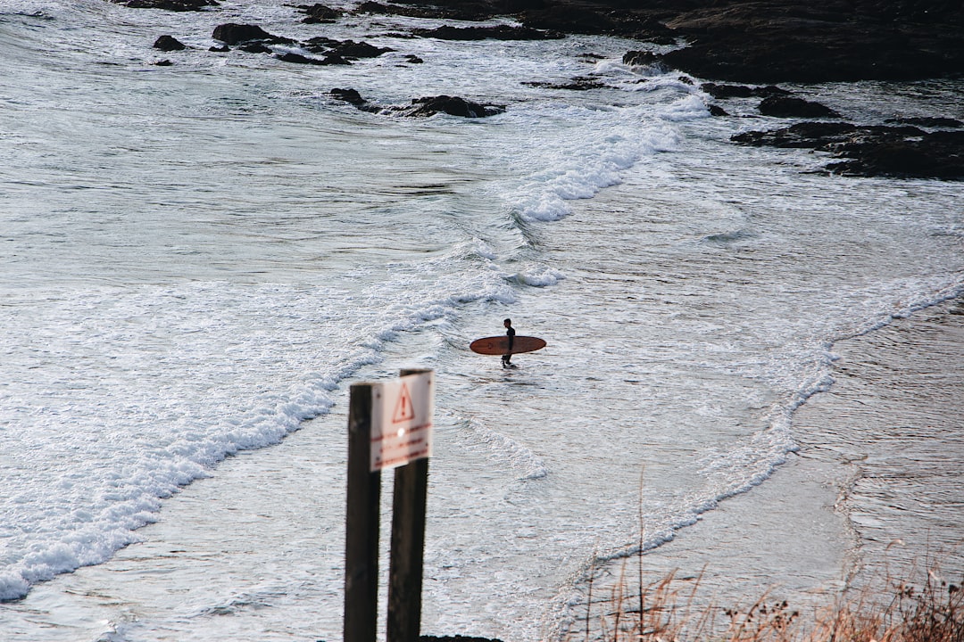 person carrying surfboard on seashore during daytime