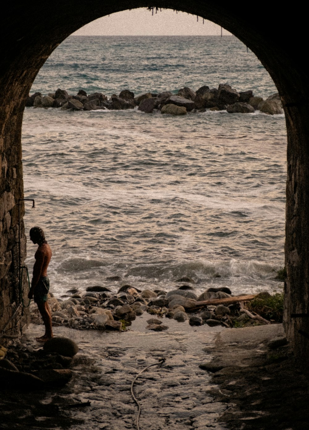 man standing in tunnel front of sea