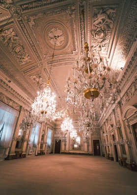 An elegant ballroom with crystal chandeliers and polished wooden floors set for a gala.