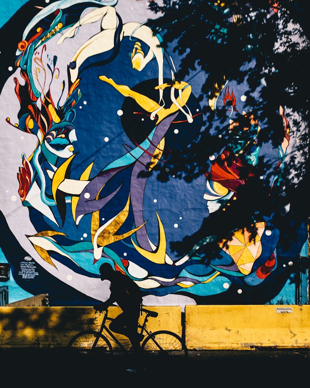 a man riding a bike past a mural on the side of a building