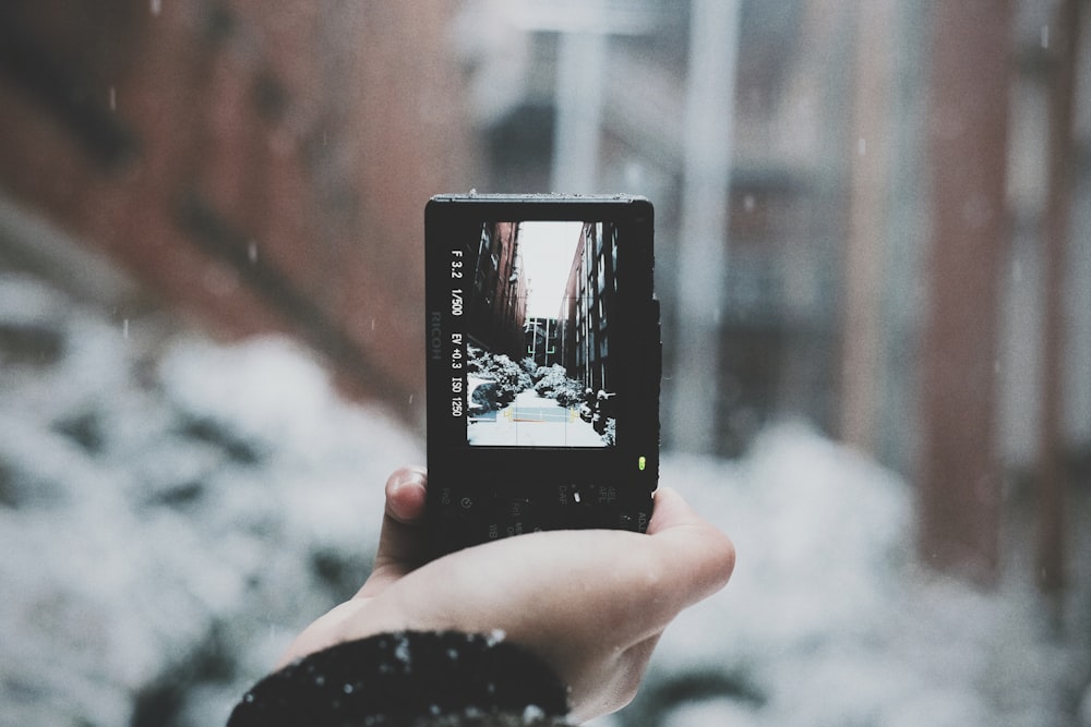 person holding black camera taking photo of buildings