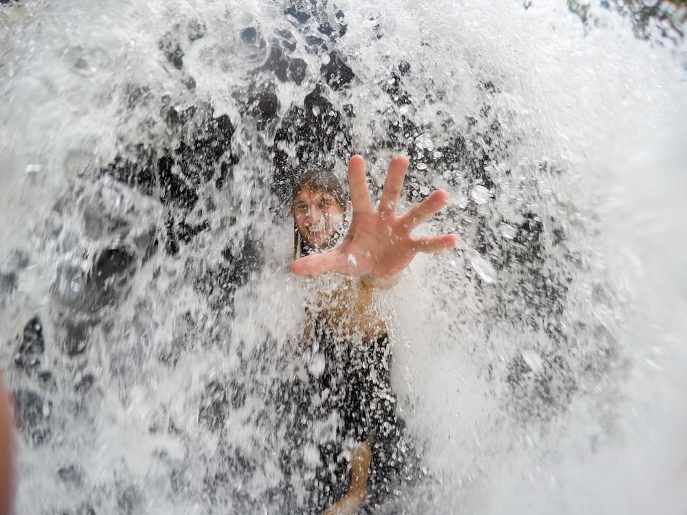 man reaching hand on waterfalls