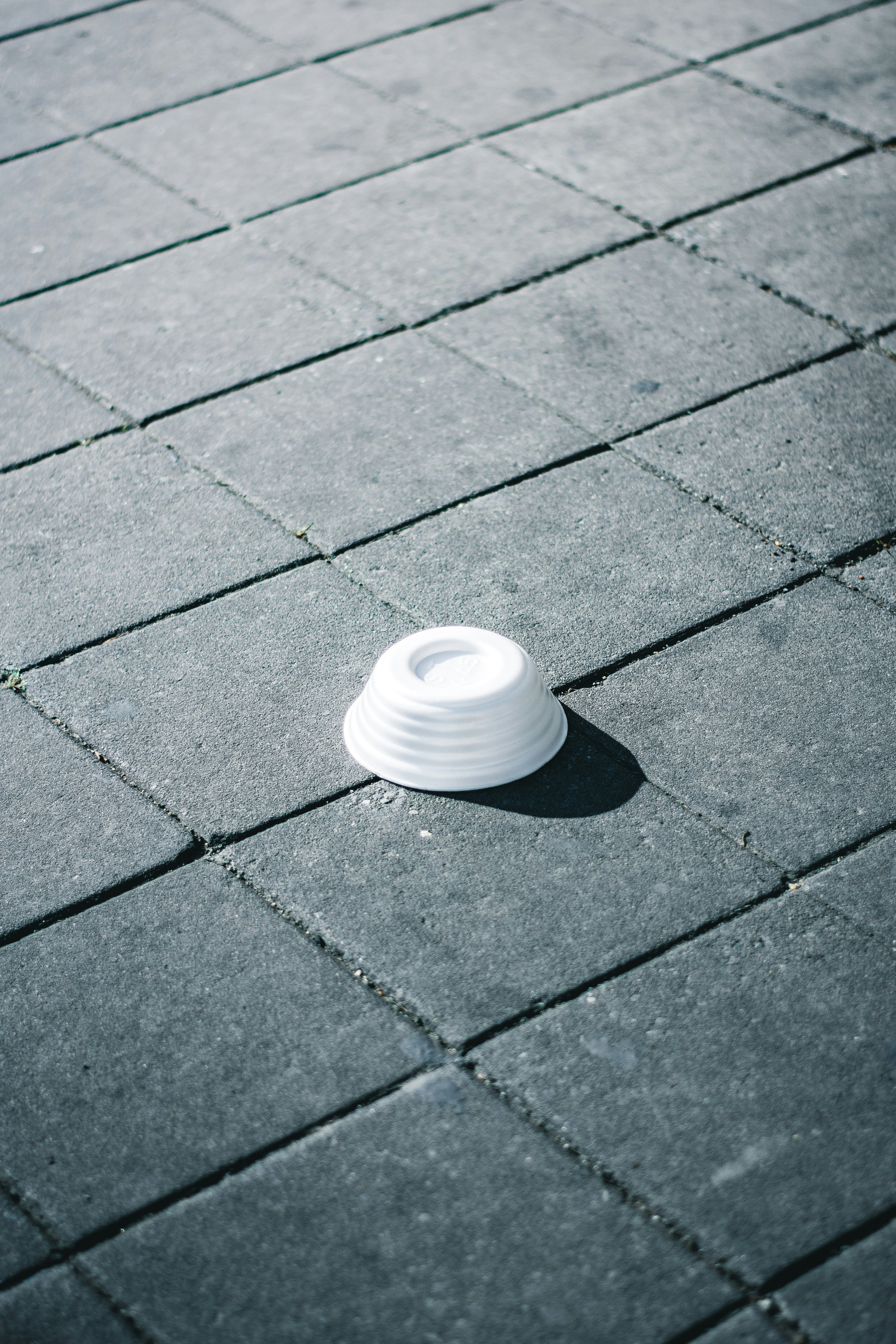 eine weiße Tasse, die auf einem Bürgersteig sitzt