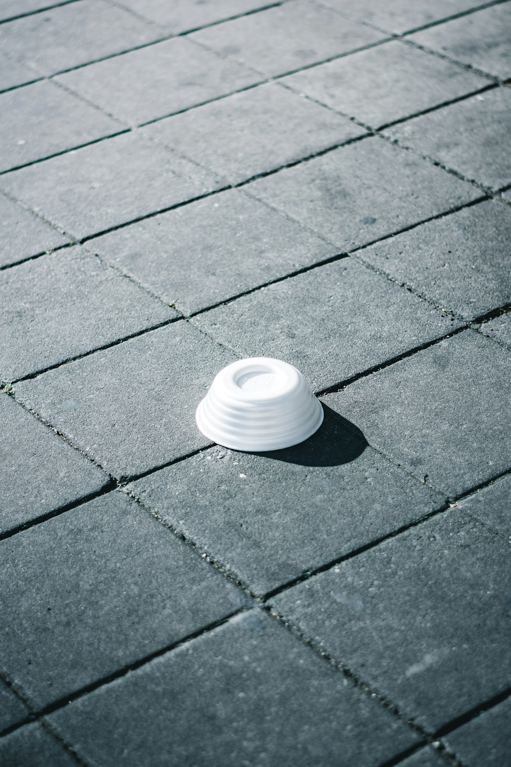 a white cup sitting on top of a sidewalk