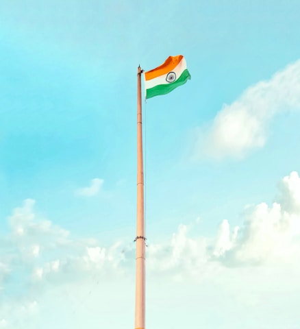 A softly lit close-up of the Indian tricolor flag waving gently against a clear sky.