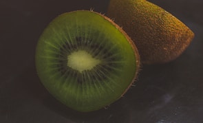 A close-up of ripe kiwis sliced open to reveal their green interior.