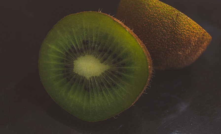 A close-up shot of a vibrant kiwi fruit sliced open, highlighting its bright green flesh and tiny black seeds.