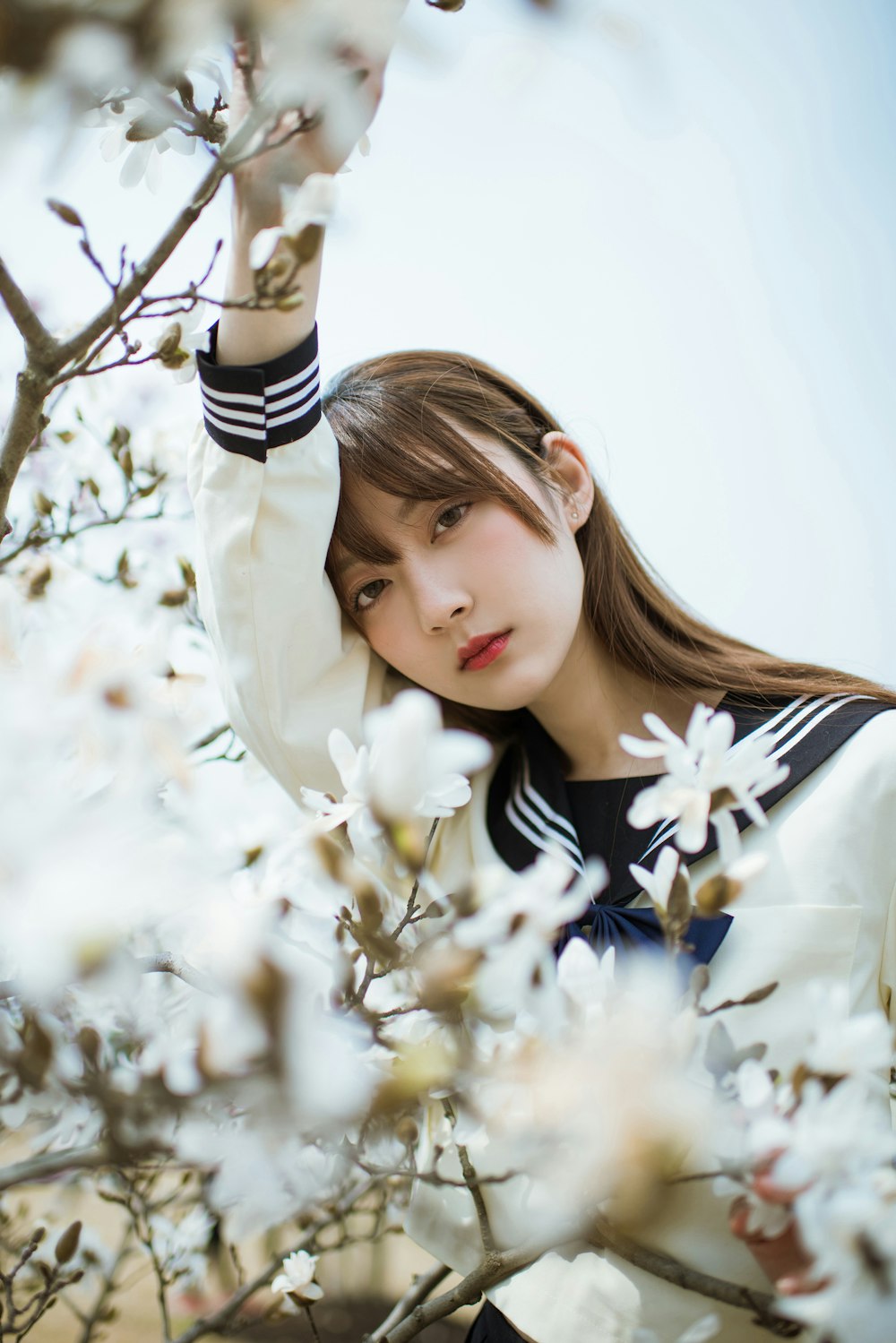 selective focus photography of girl standing beside petaled flowers during daytime