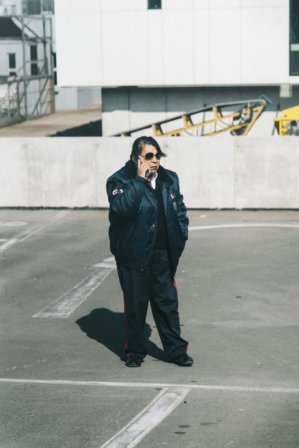 a man standing in a parking lot talking on a cell phone