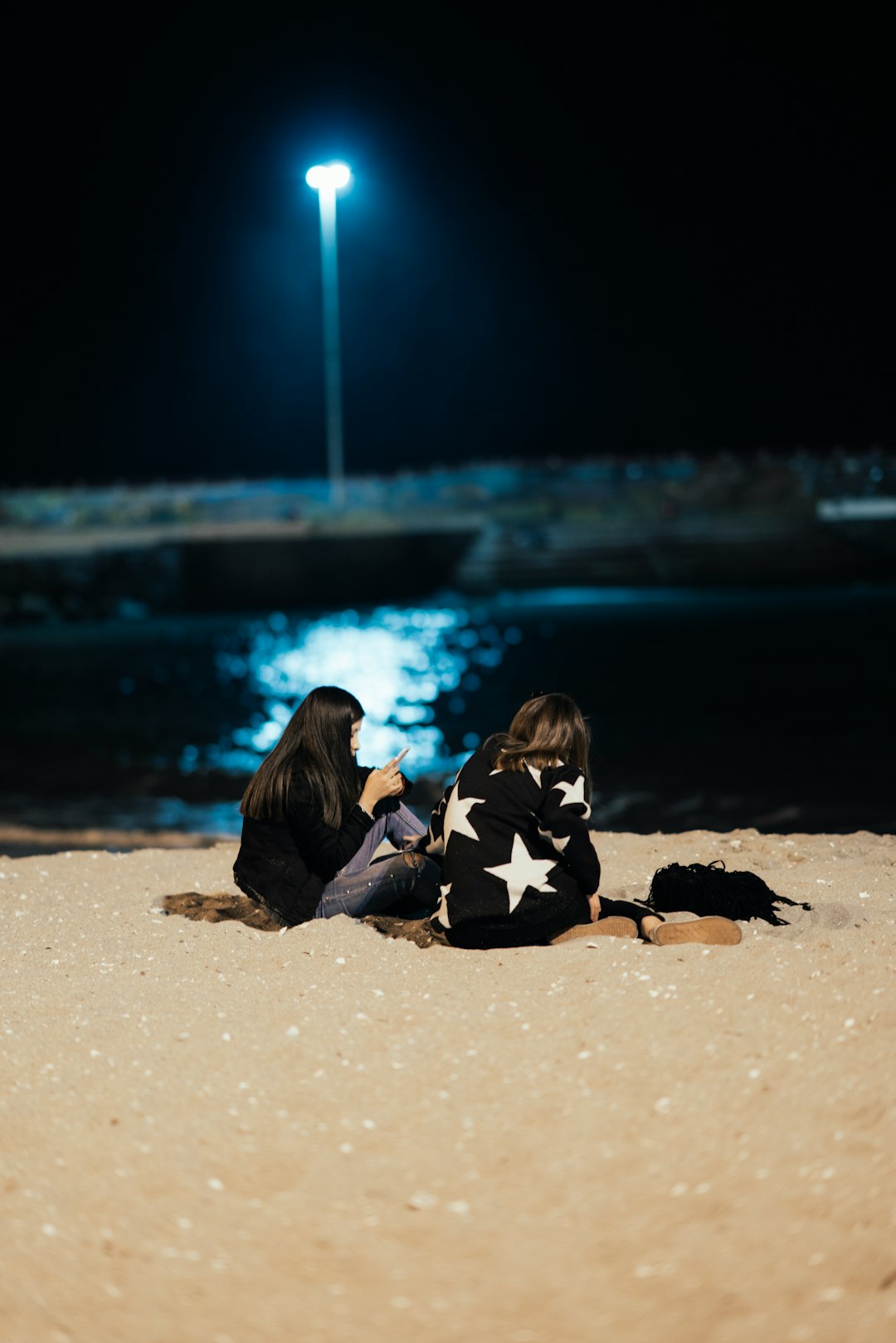 woman wearing white and black pullover sitting on brown sand