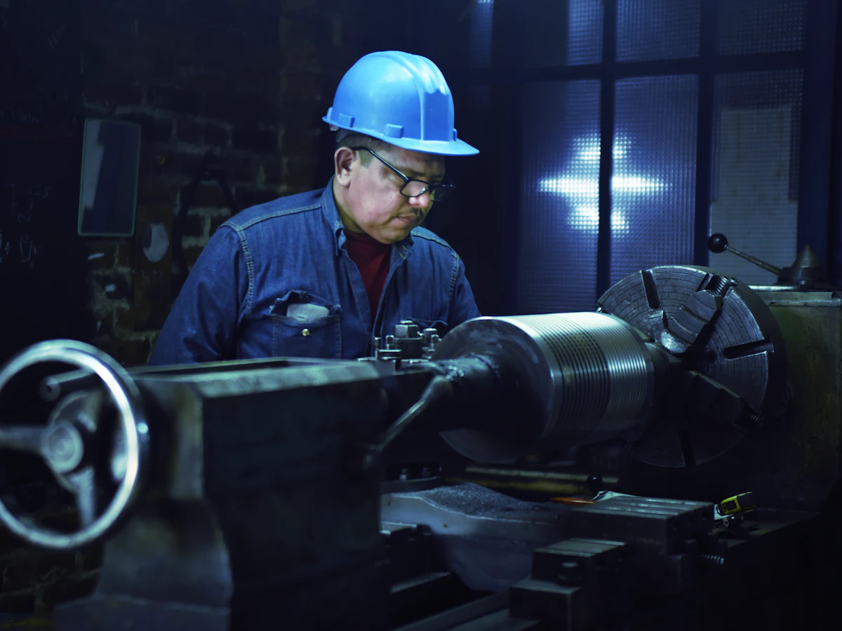 Operario con casco trabajando en un torno industrial