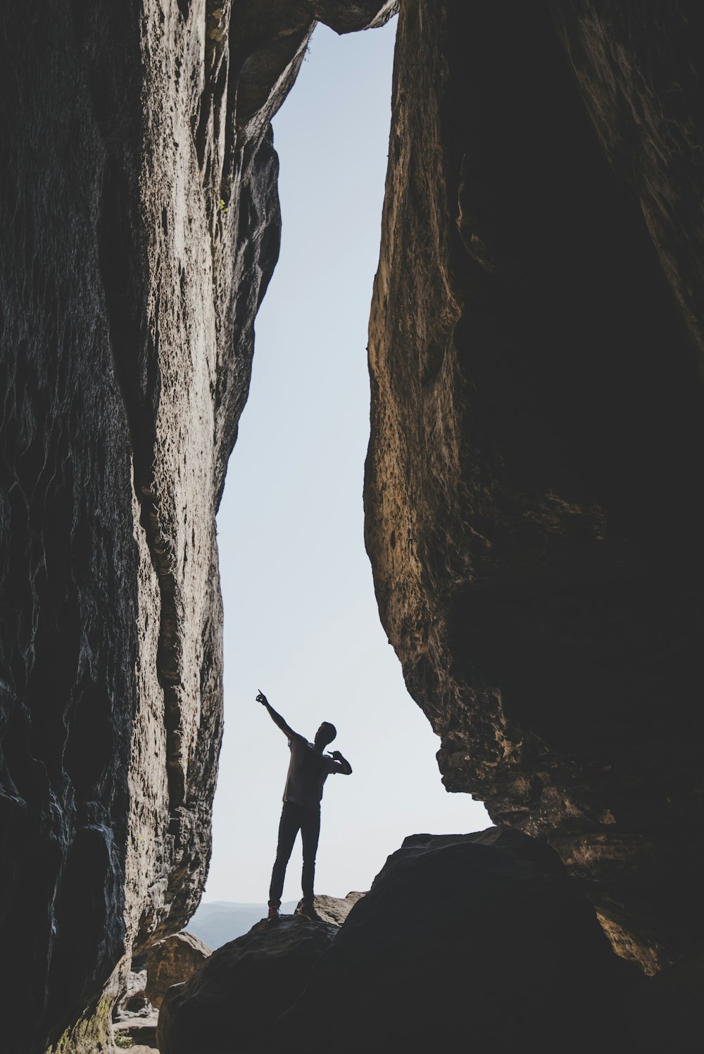 man standing beside rock formation during daytime