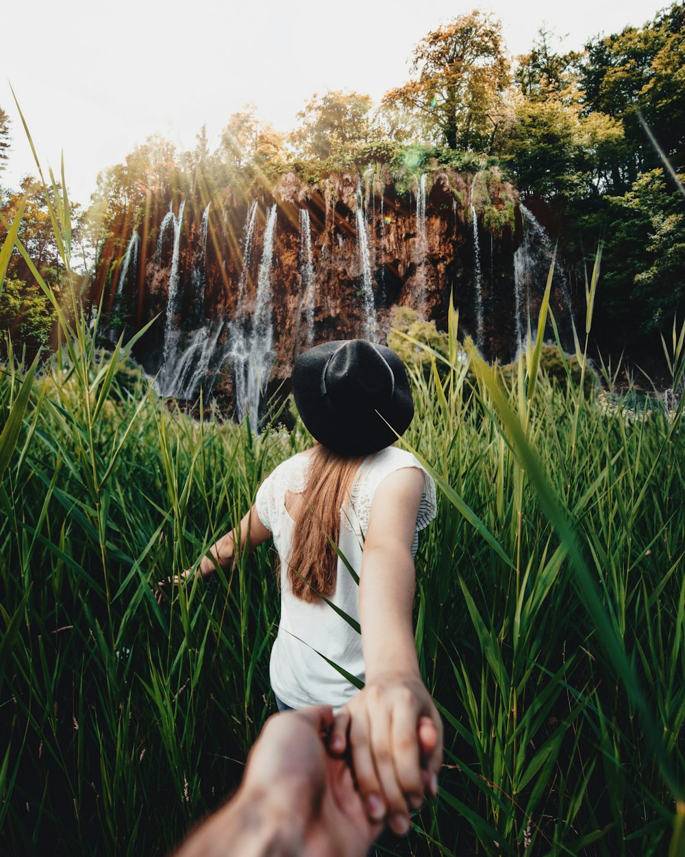 woman standing near tall grass field during daytime