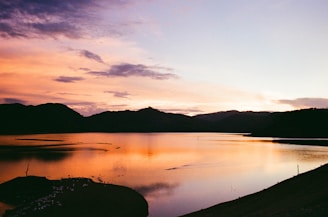 A vibrant sunset over a tranquil lake surrounded by mountains.