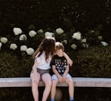 two toddler girl and boy sitting on concrete bench near outdoor during daytime