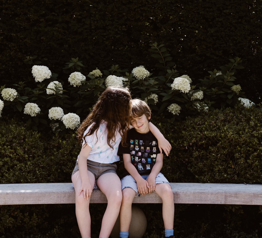 duas meninas e meninos sentados em banco de concreto perto ao ar livre durante o dia