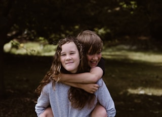 boy riding girl's back during day