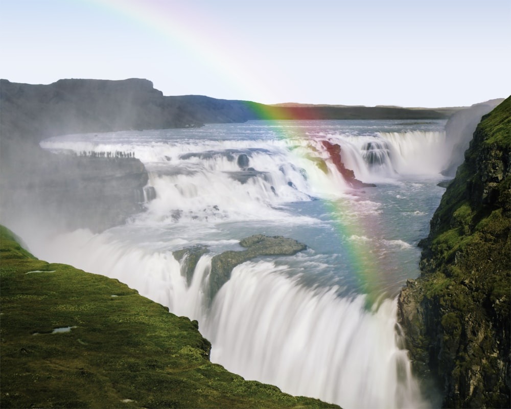 a rainbow in the sky over a waterfall