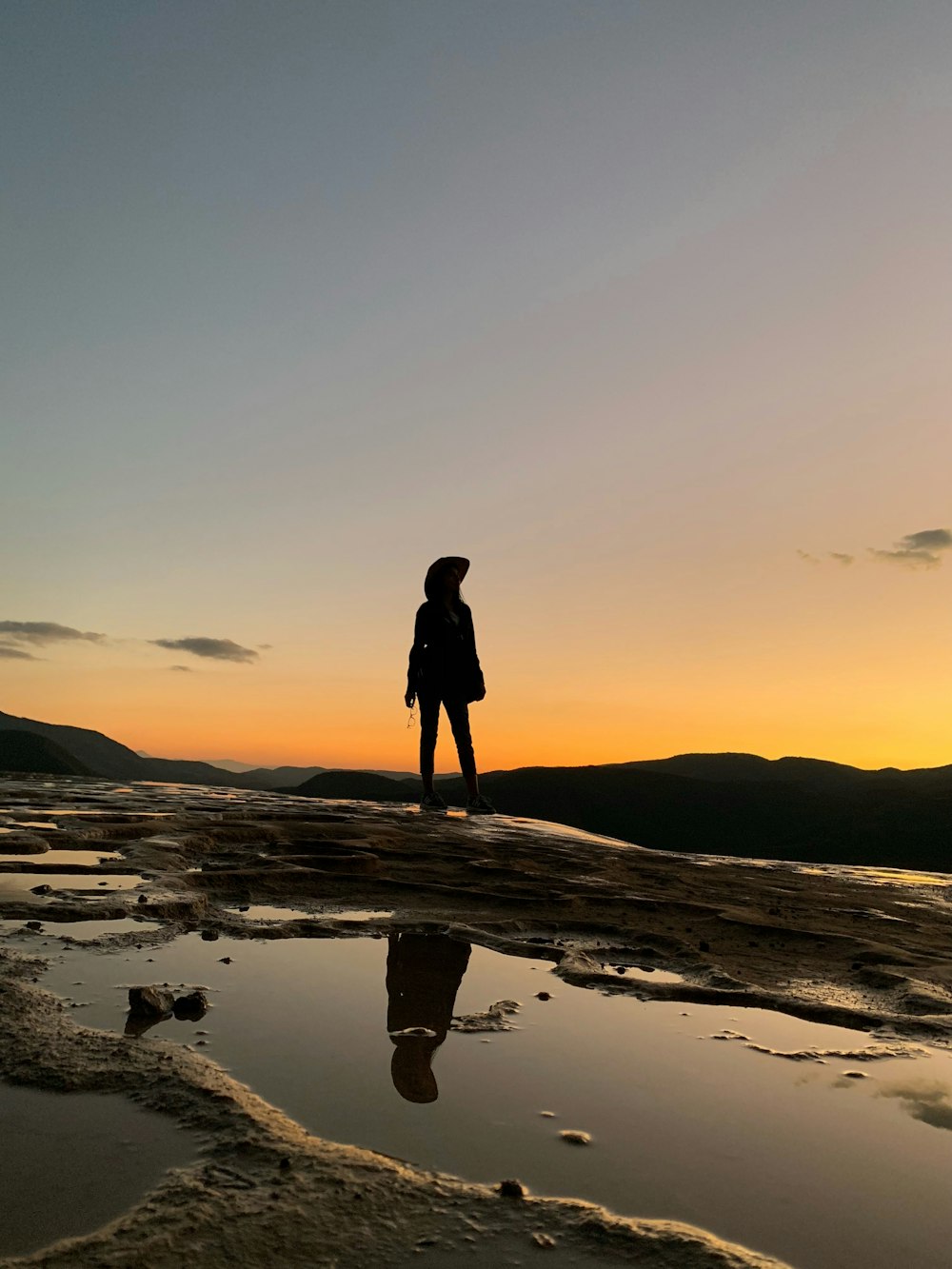 person standing near cliff facing towards mountain