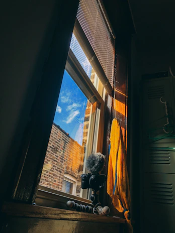 A cozy studio corner with a camera on a tripod and soft natural light streaming through a window.