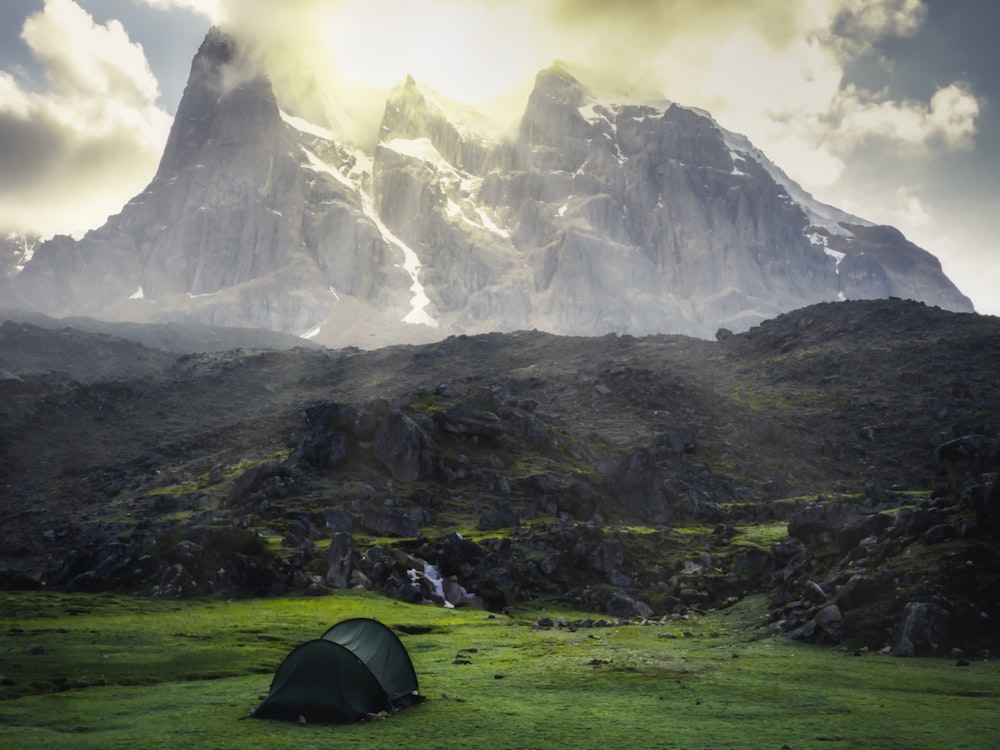 green dent on grass field with view of mountain during daytime