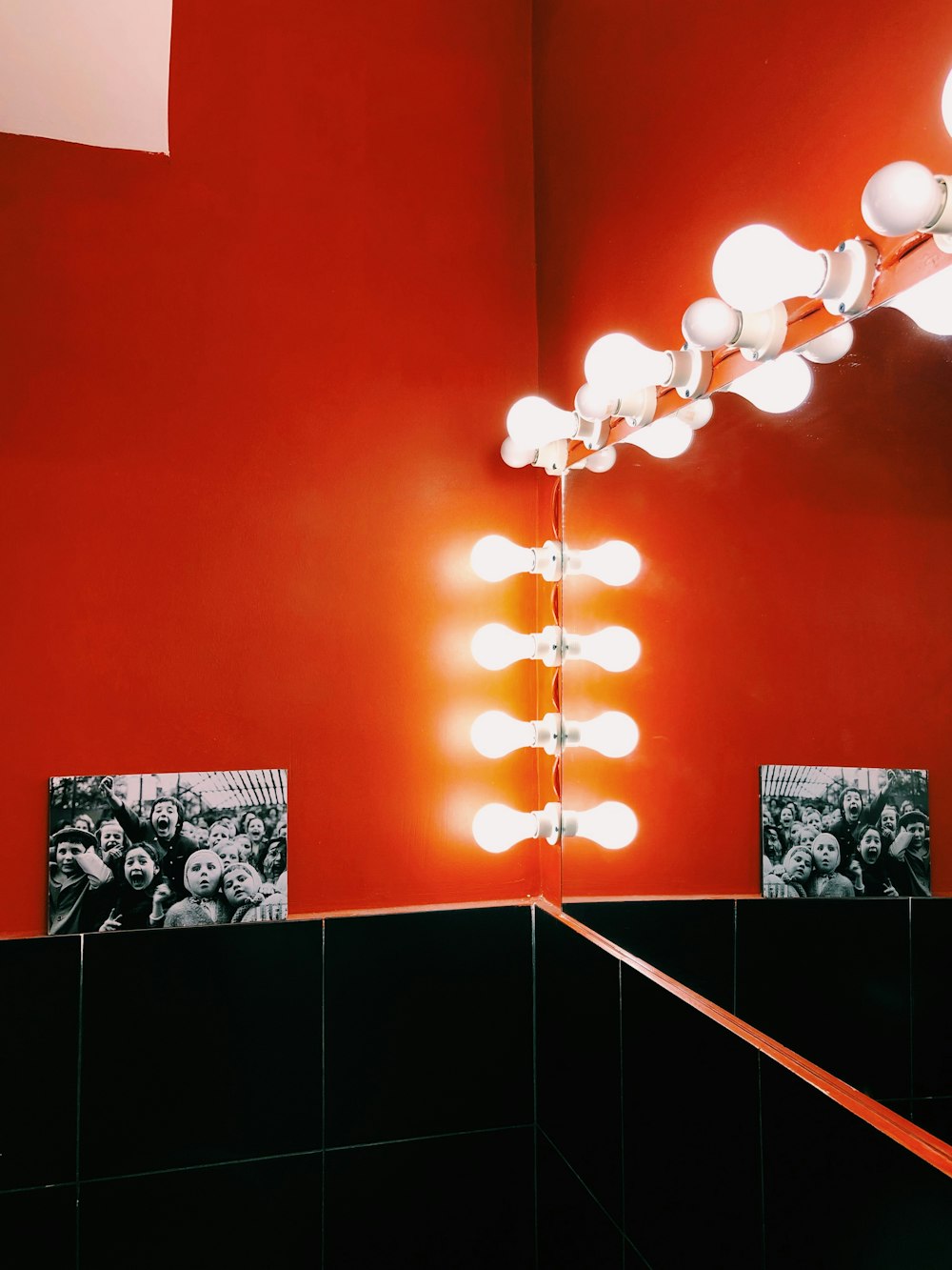 a bathroom with a red wall and a lighted mirror