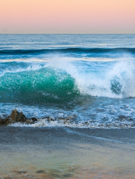 A neon blue and pink stylized wave crashing against a tropical beach at sunset.