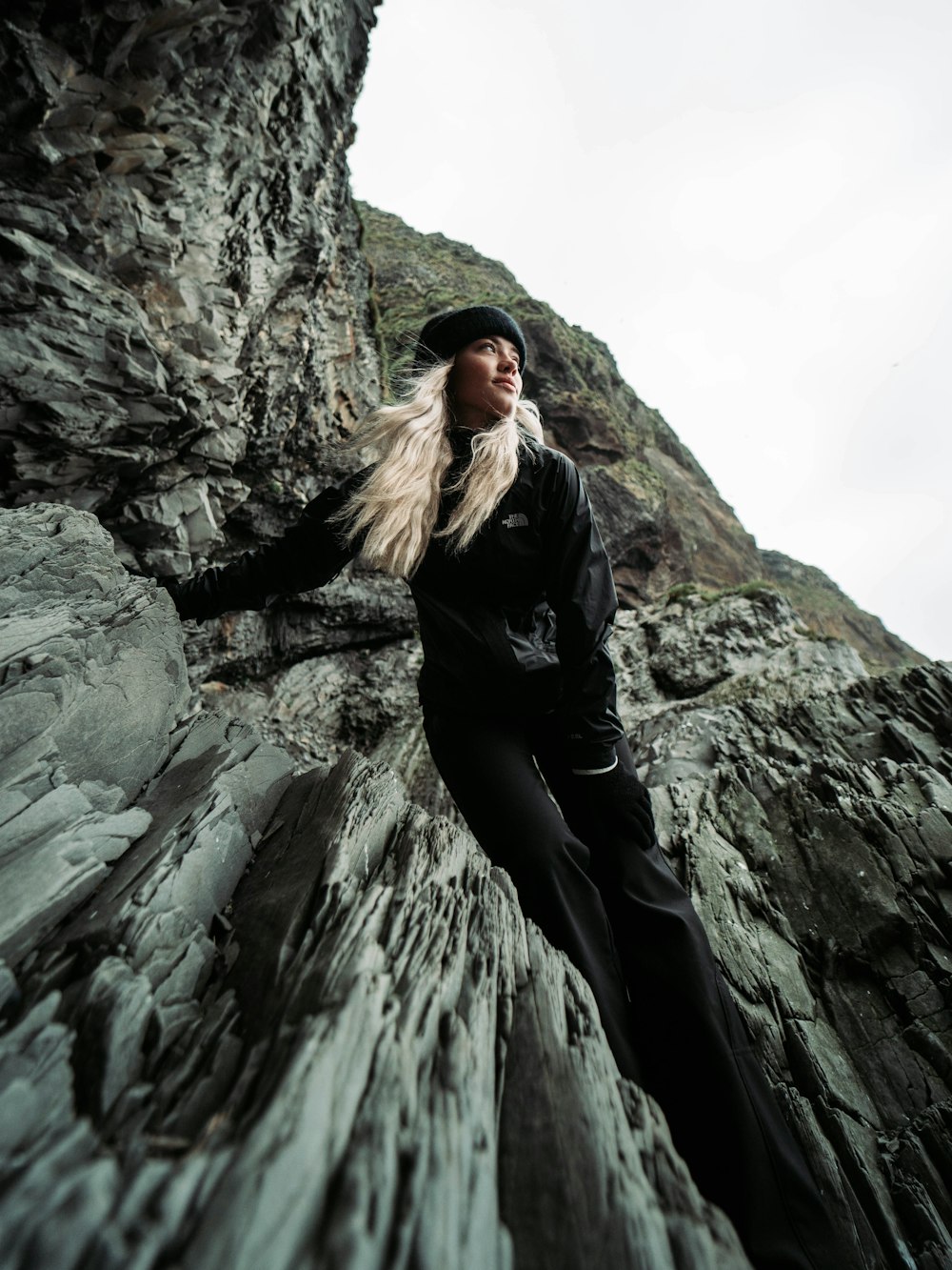 woman in black suit climbing clif