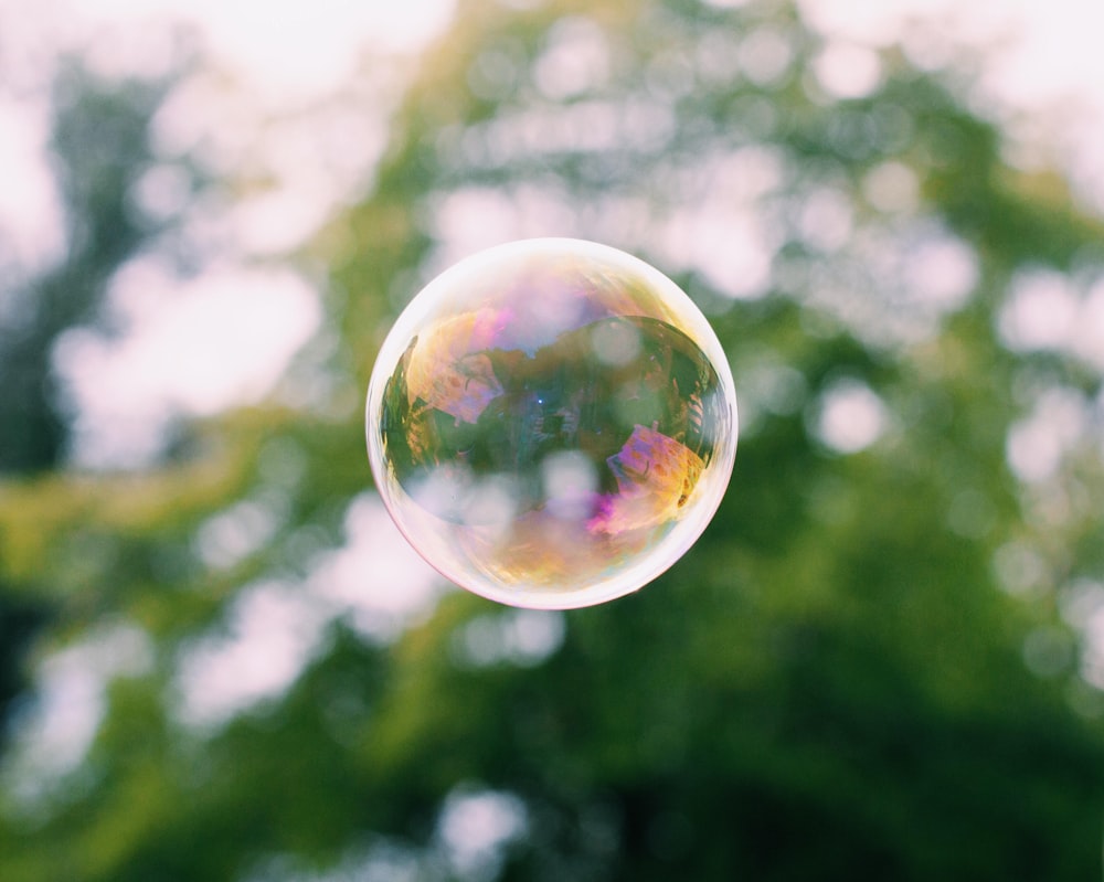 a close up of a soap bubble with trees in the background