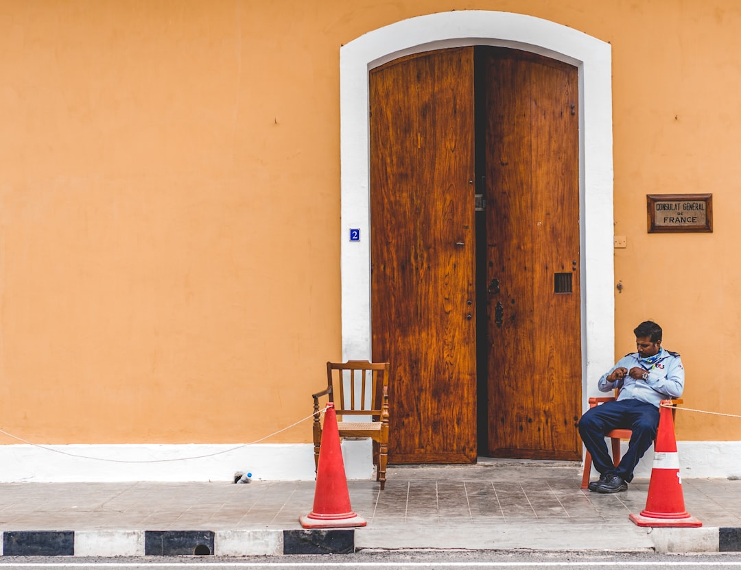 photography of man sitting on chair beside opened door during daytime
