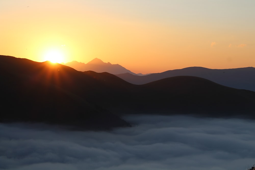 the sun is setting over a mountain range