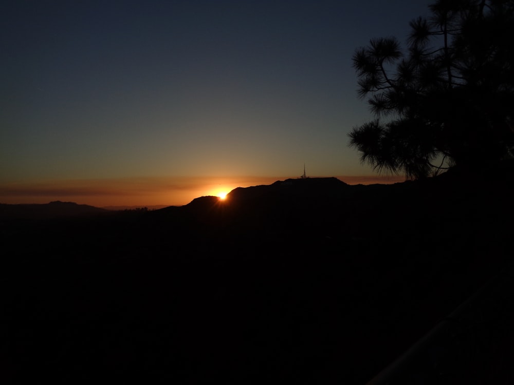 the sun is setting over a mountain range