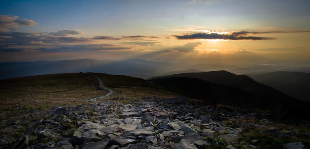 the sun is setting over a rocky mountain