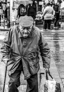 grayscale photo of man walking and holding handbag