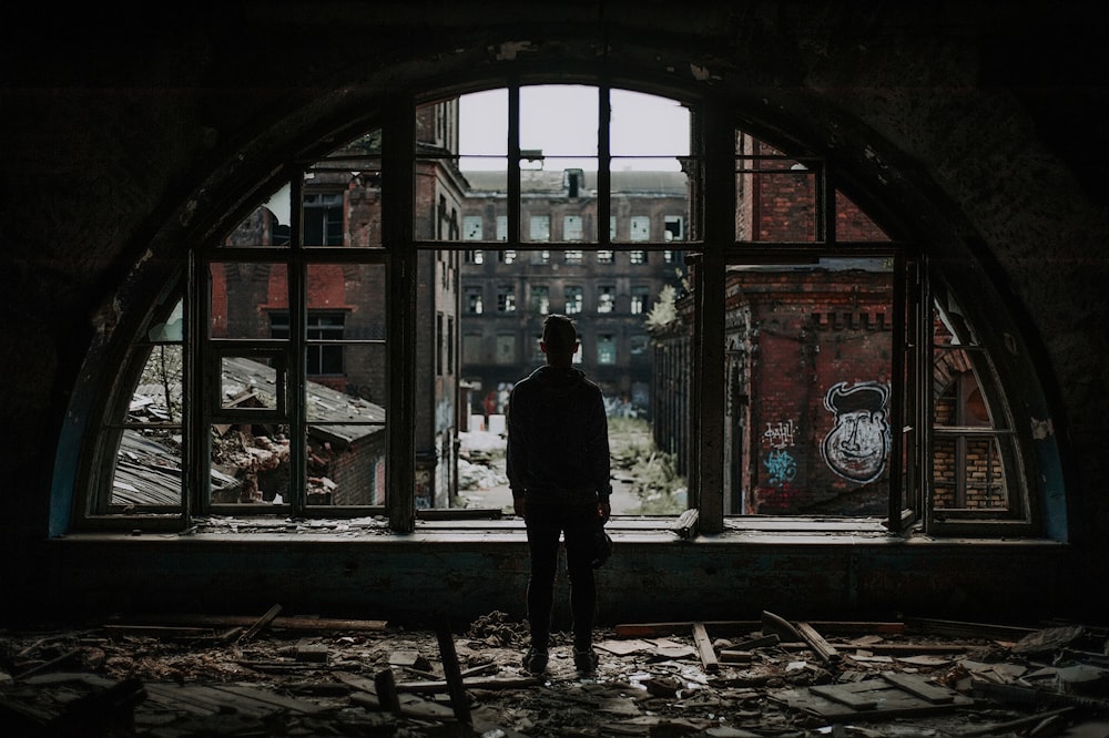 a man standing in front of a window in an abandoned building