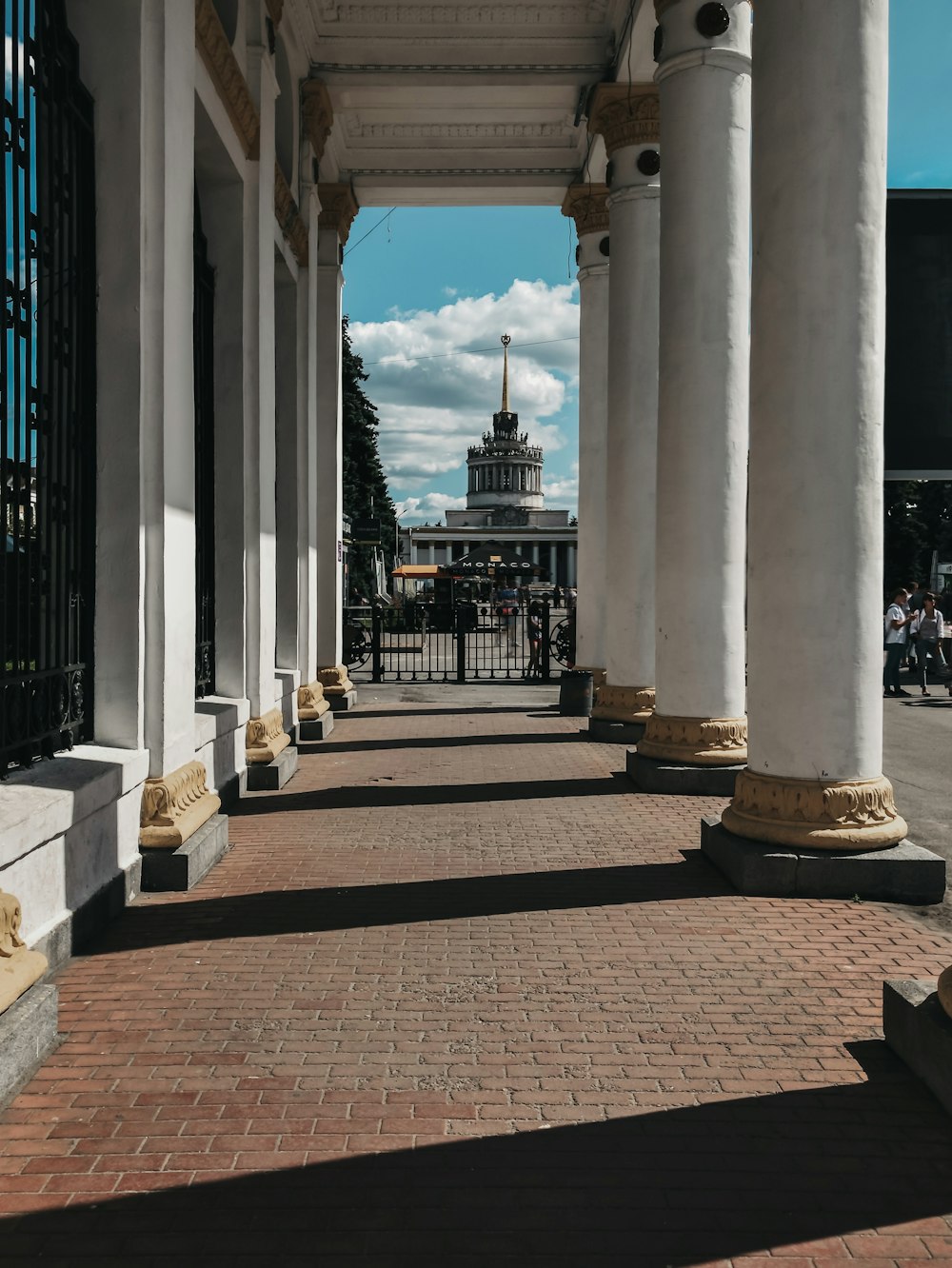 a row of white pillars with a clock tower in the background