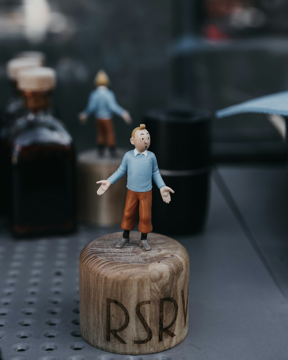 une petite figurine d’une personne debout sur un bloc de bois