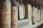 A collection of dusty, vintage wine bottles lined up on a wooden shelf. The bottles have aged labels featuring ornate designs and faded text. The atmosphere suggests antiquity and nostalgia.