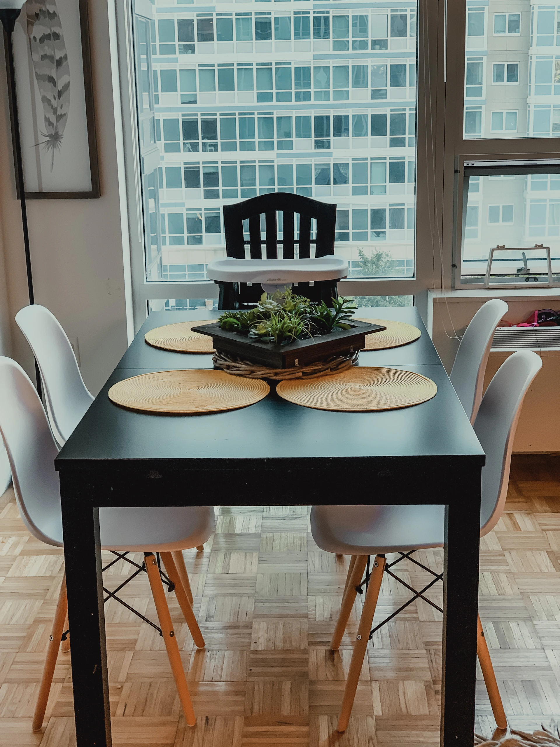 Modern dining table with sleek chairs, decorated with a vibrant centerpiece, set against a bright window.