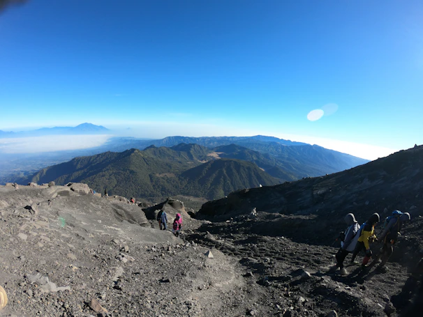 A rugged hiking backpack set on a rocky trail with a panoramic mountain view at sunrise.