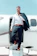A smiling business traveler stepping onto a sleek private jet under a clear blue sky.