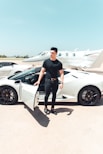 man in black by a white sports car