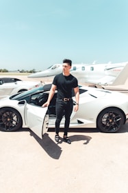 man in black by a white sports car