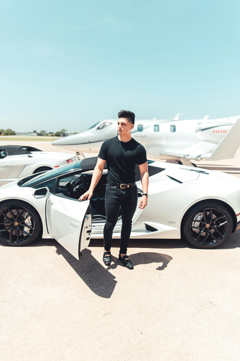 Homem de preto por um carro esportivo branco