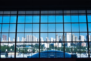 A large clear glass window showcasing a city view from inside a condo.