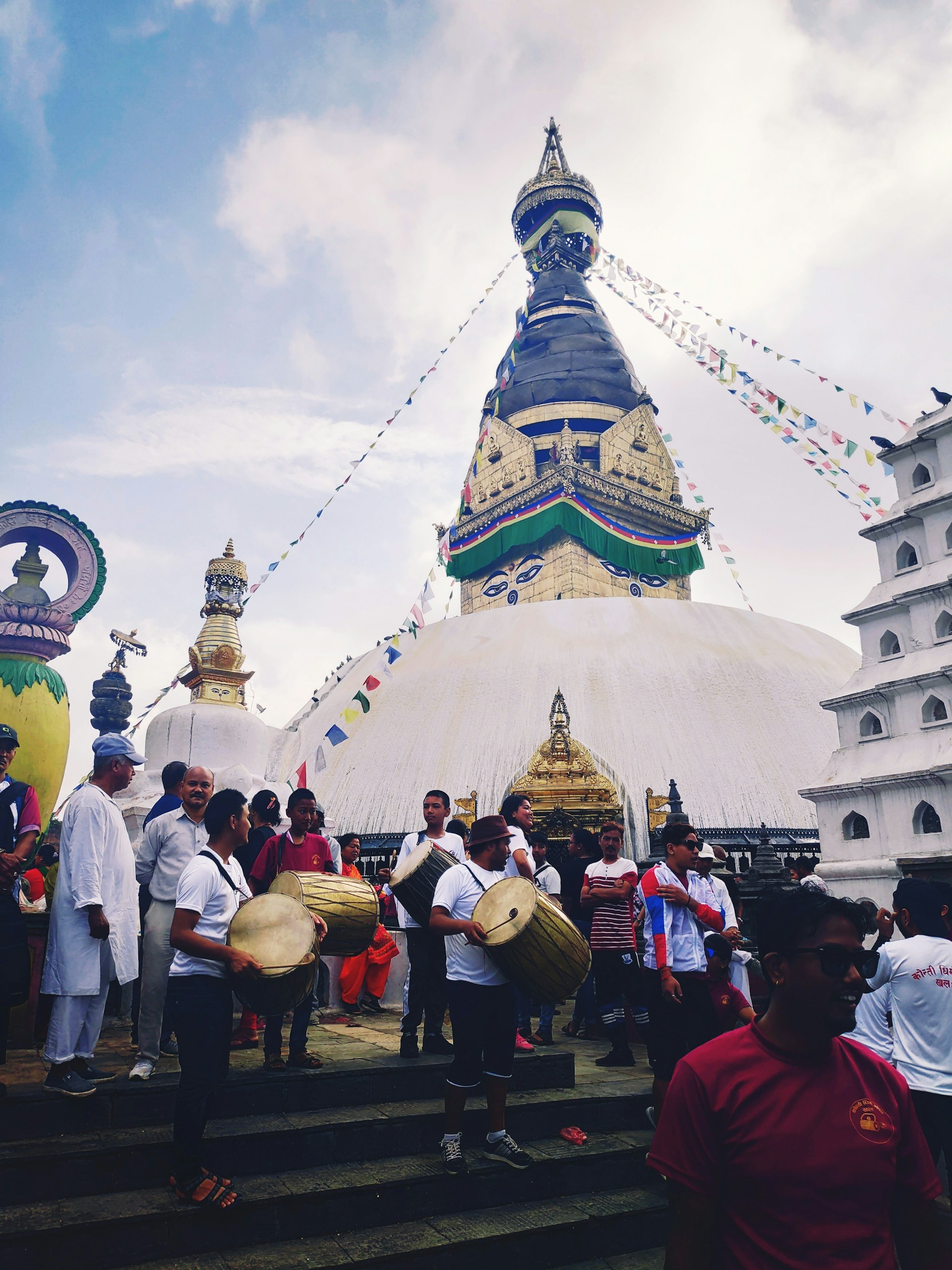 A colorful festival scene at Bodh Gaya, with monks and visitors celebrating under fluttering prayer flags near the Mahabodhi Temple.