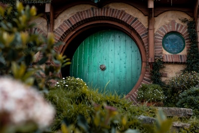 A cozy wooden door with a small window, surrounded by lush greenery outside.