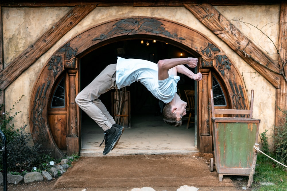 man jumping in front of house