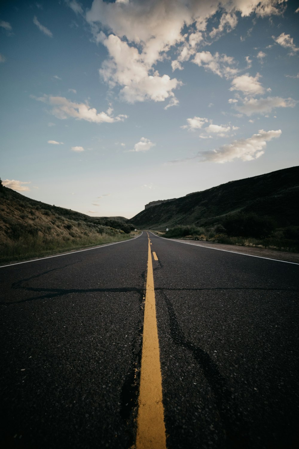 gray concrete road with no vehicle under blue and white skies